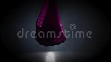 女子空中体操运动员在马戏团舞台上表演紫罗兰丝绸。 精彩的杂技表演